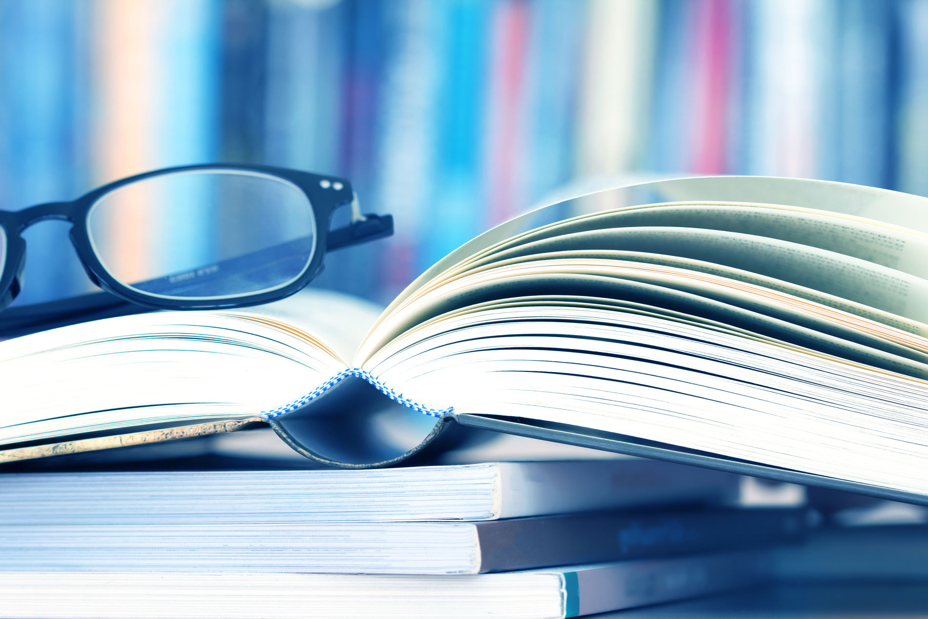A stack of books with reading glasses on top.